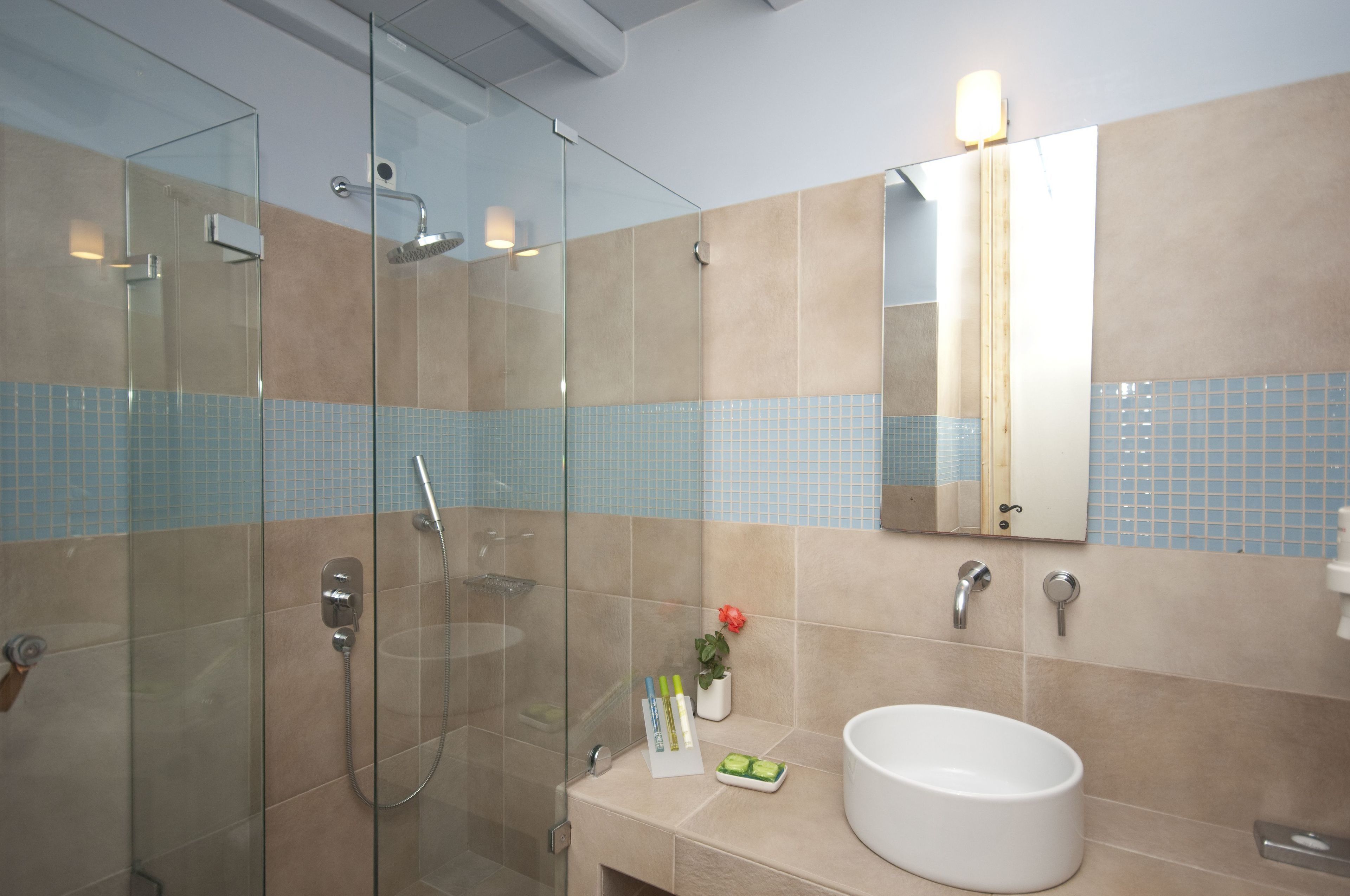 Une salle de bain moderne avec une douche à parois de verre, un lavabo blanc et un miroir au-dessus.