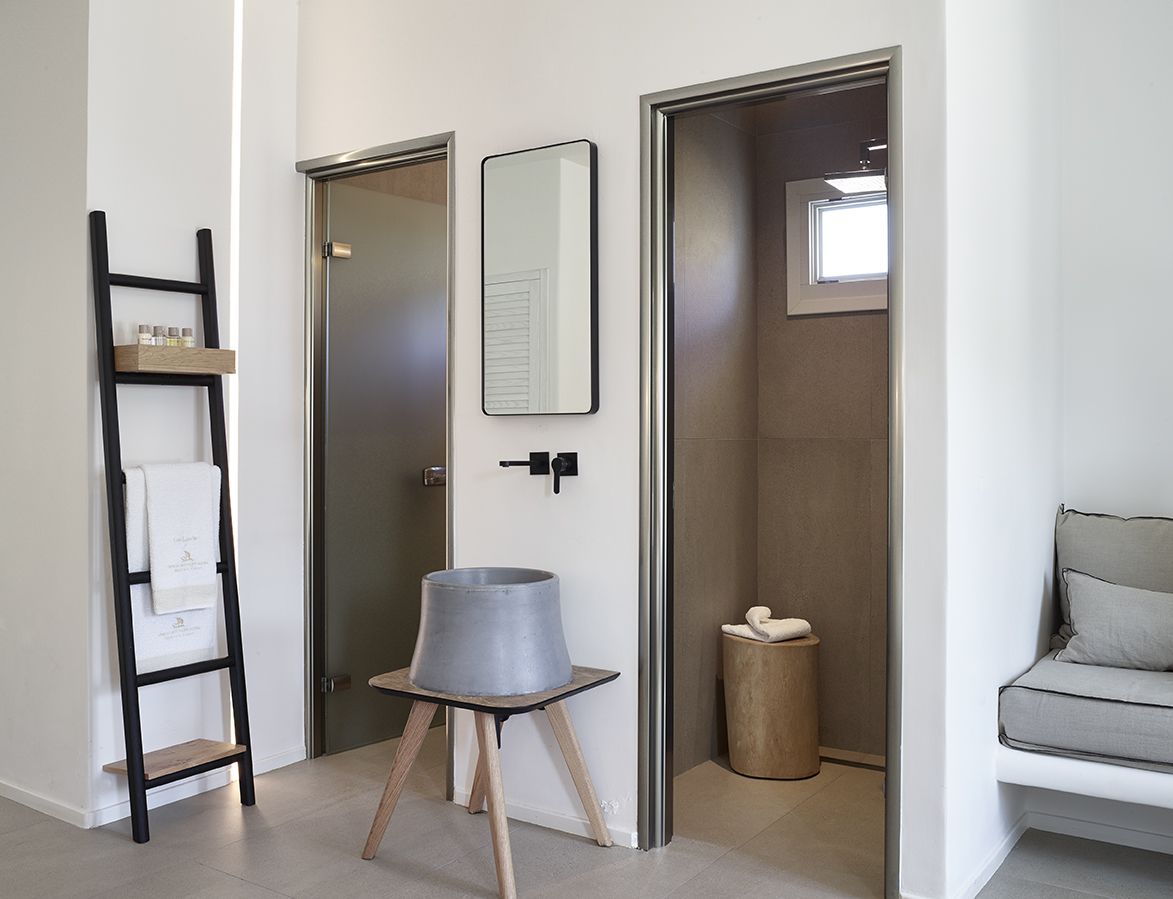 Un baño moderno con ducha, toallero, espejo y una mesita con lavamanos.