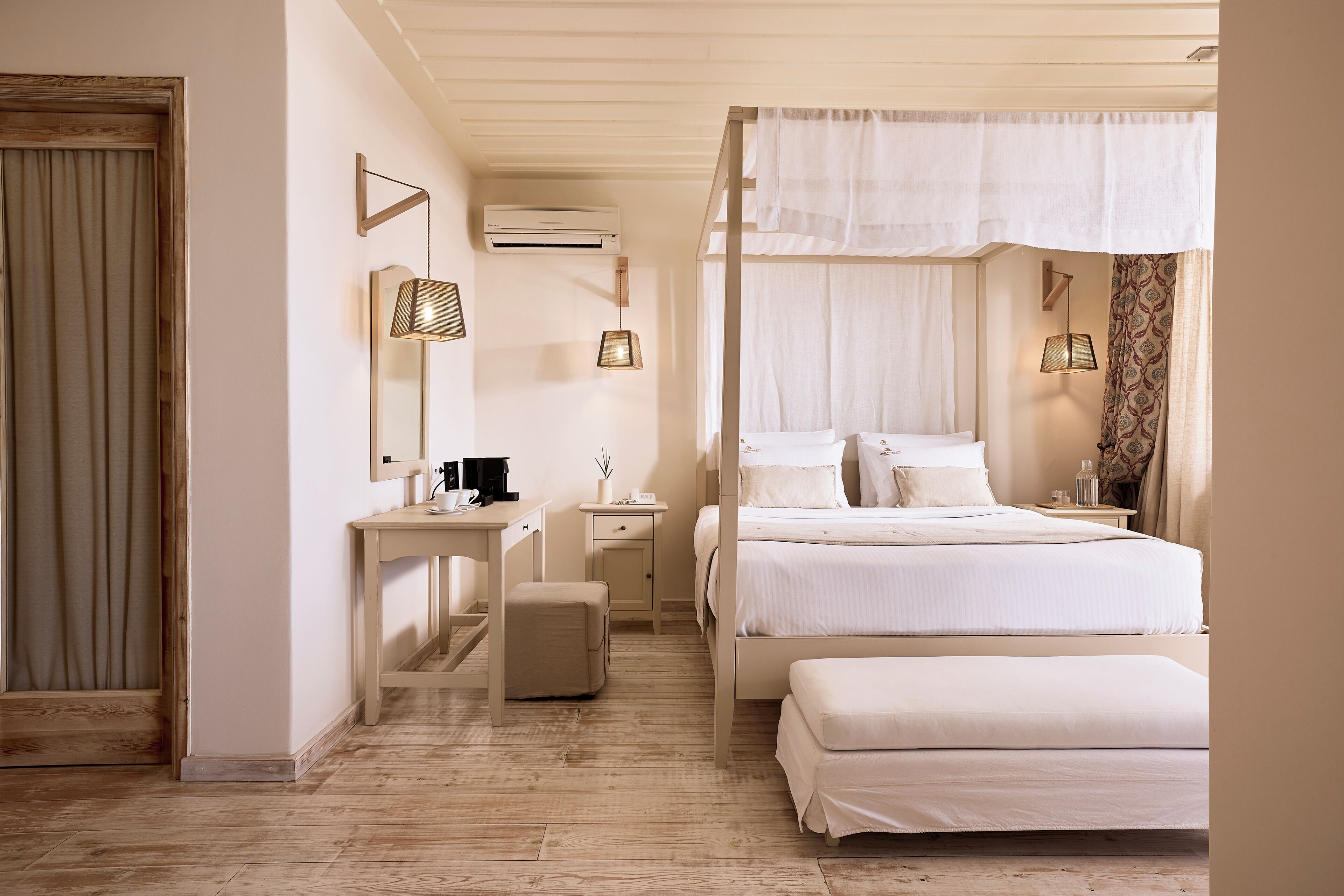 A bedroom with a bed, bedside tables, a desk, an air conditioning unit, and a window with curtains.