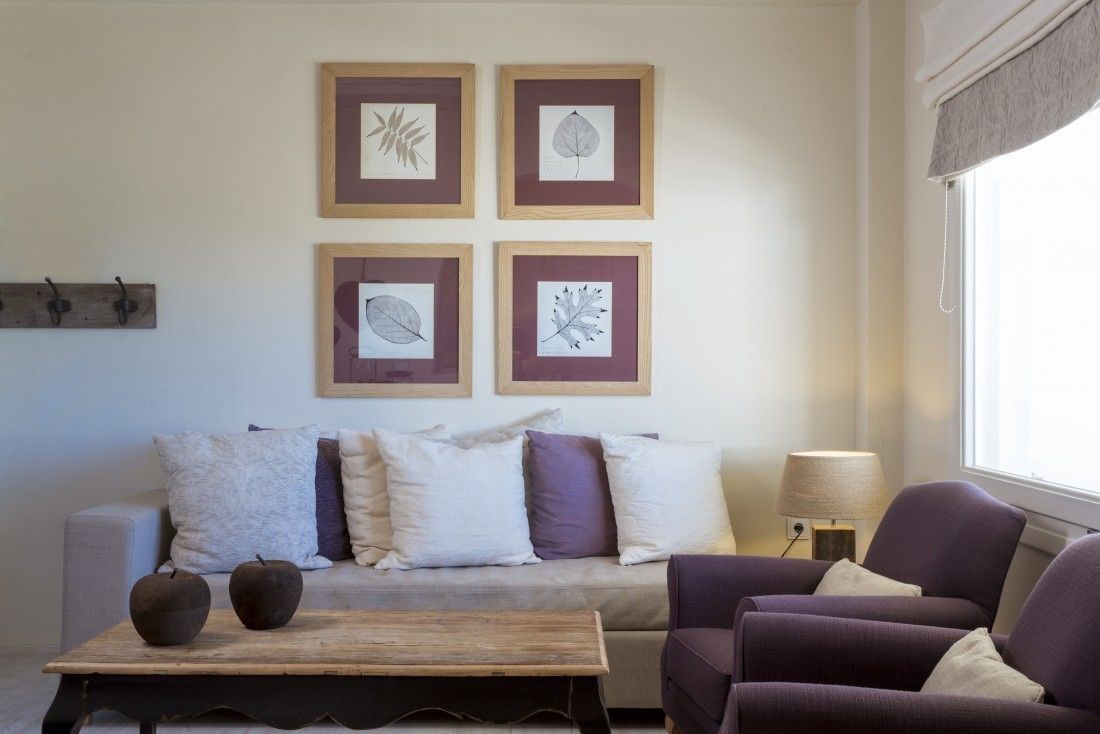 A living room with a sofa, two armchairs, a coffee table, and four framed leaf artworks on the wall.