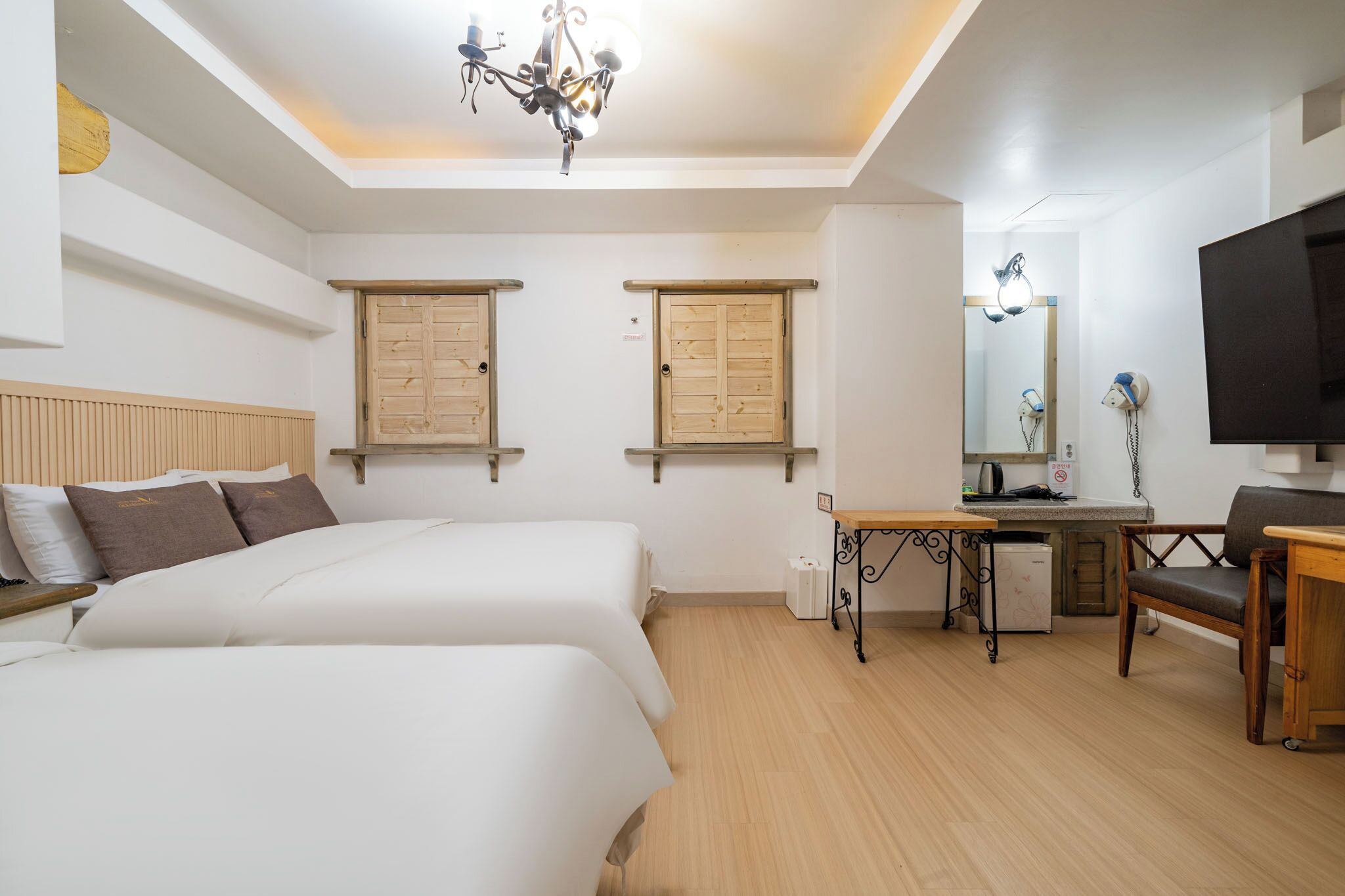 Habitación de hotel con dos camas, un escritorio, una silla, un televisor y una lámpara en el techo.