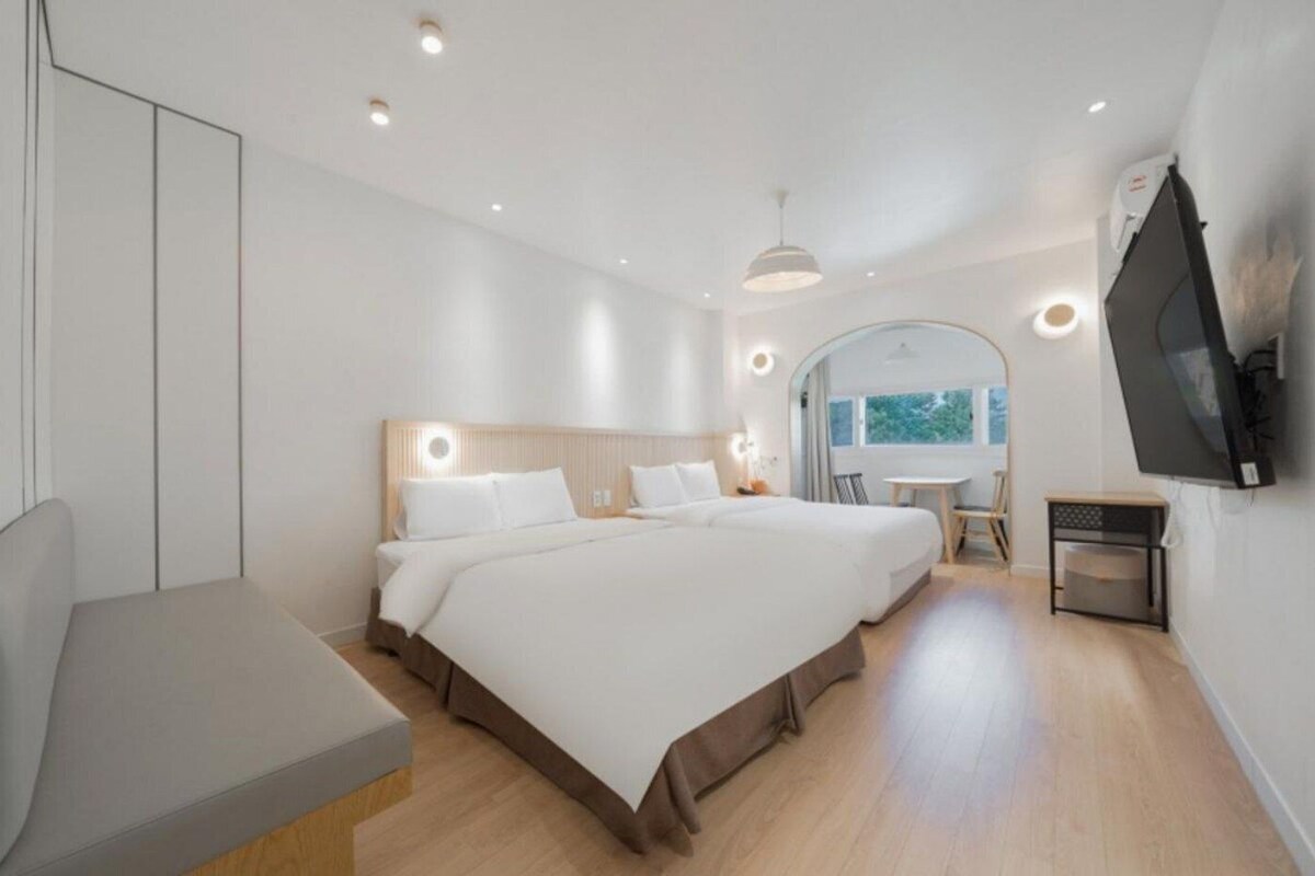 Een moderne hotelkamer met een groot bed, een zithoek, een aan de muur bevestigde televisie en een raam met uitzicht.