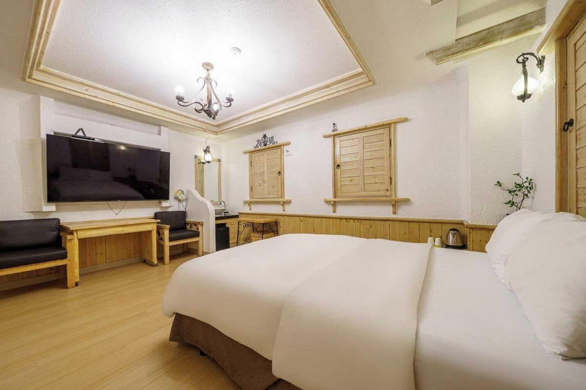 Een hotelkamer met een bed, een bureau met stoel, een televisietoestel en een kroonluchter.