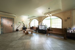 A spacious lobby with a wooden bench, a display case, and a statue.