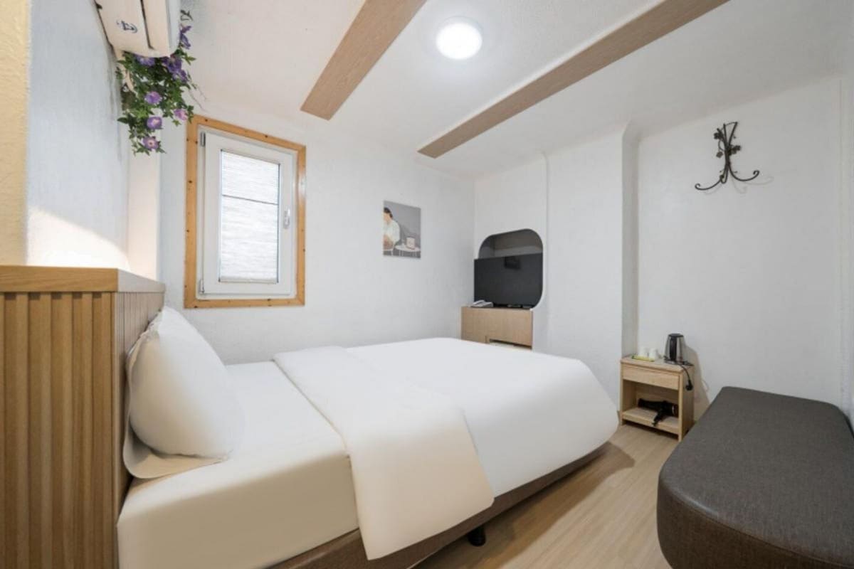 Een slaapkamer met een bed, nachtkastje en een klein bureau met een stoel.