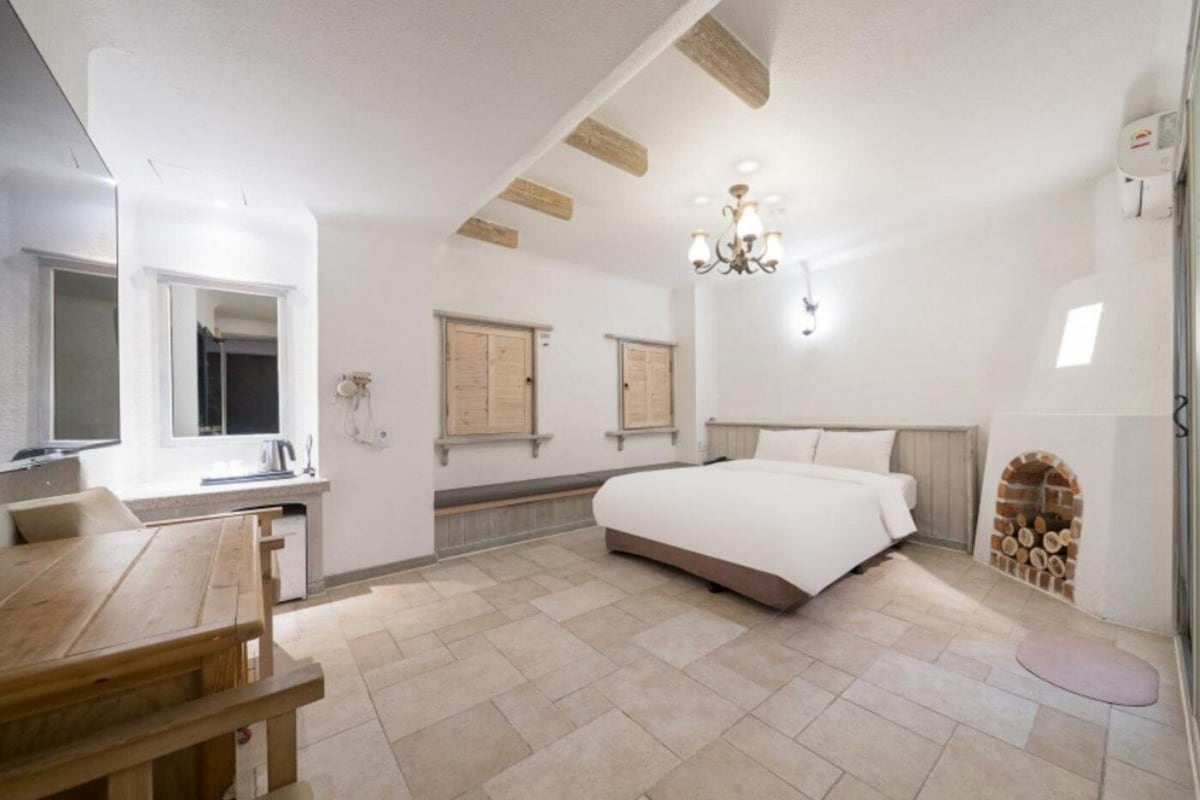 Een slaapkamer met een groot bed, een houten bureau, een kroonluchter en een open haard.