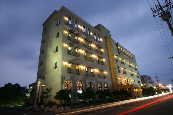 A multi-story hotel with illuminated windows and balconies, featuring a classic architectural style with arched windows and a central entrance. - Incheon Airport Hotel Oceanside (Incheon)