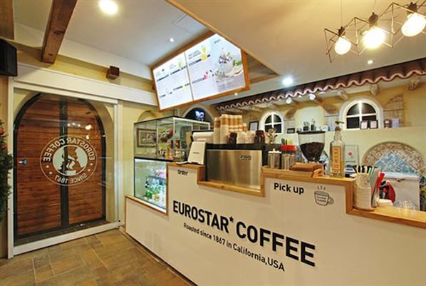 A coffee shop interior with a wooden door, a pick-up counter, and a menu display. - Incheon Airport Hotel Oceanside (Incheon)