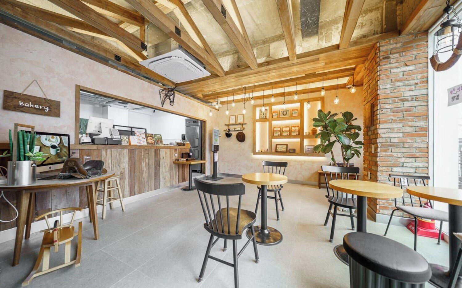 Un café acogedor con muebles de madera, un letrero de panadería y una pared de ladrillo.