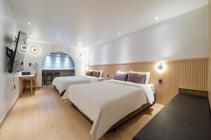 A modern hotel room with two beds, a desk, and a mirror.