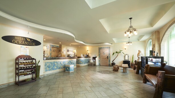 A hotel lobby with a reception desk, a wine rack, and a seating area with wooden benches.
