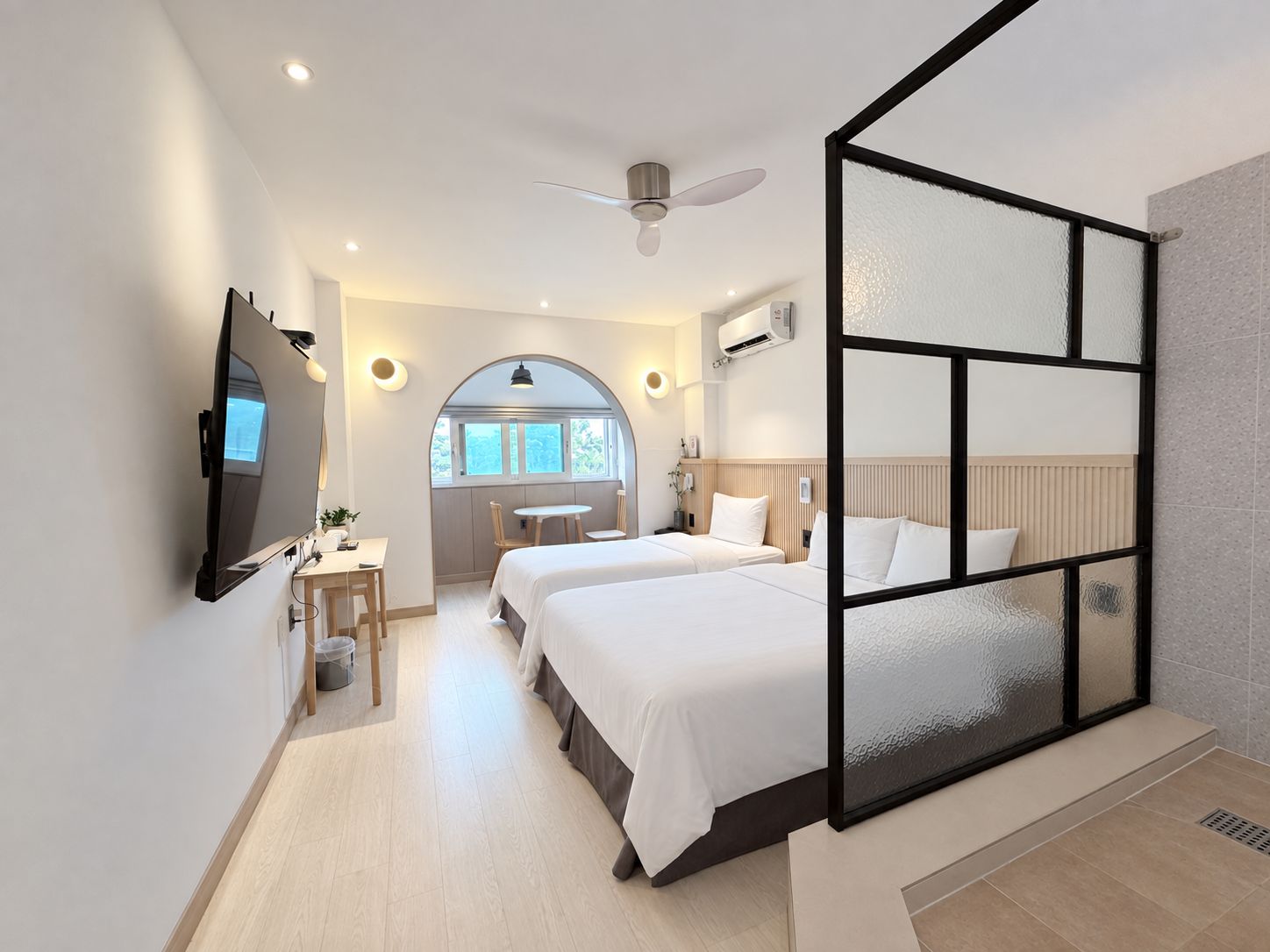 Una habitación de hotel moderna con una cama grande, un escritorio y vistas al exterior.