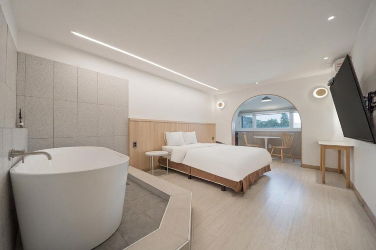 Een moderne slaapkamer met een ruime badkuip, een bed en een werkplek.