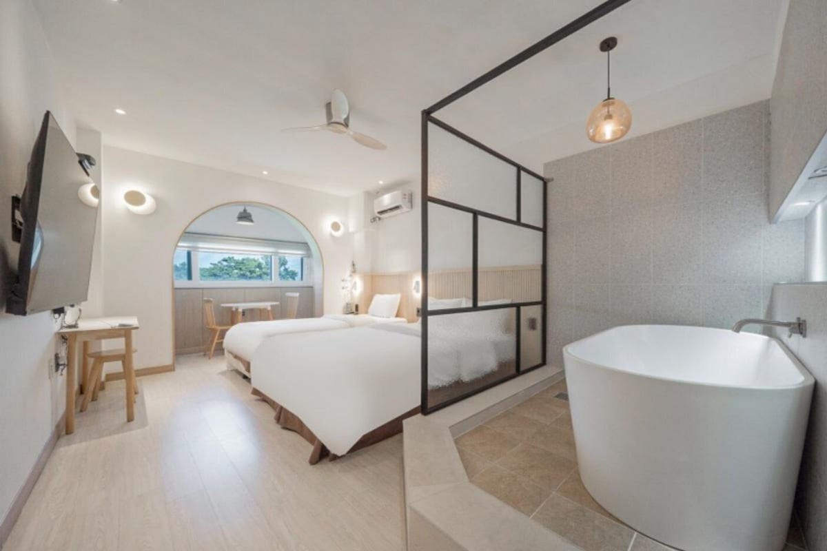 Een moderne hotelkamer met een groot bed, een aparte zithoek en een ruim bad.