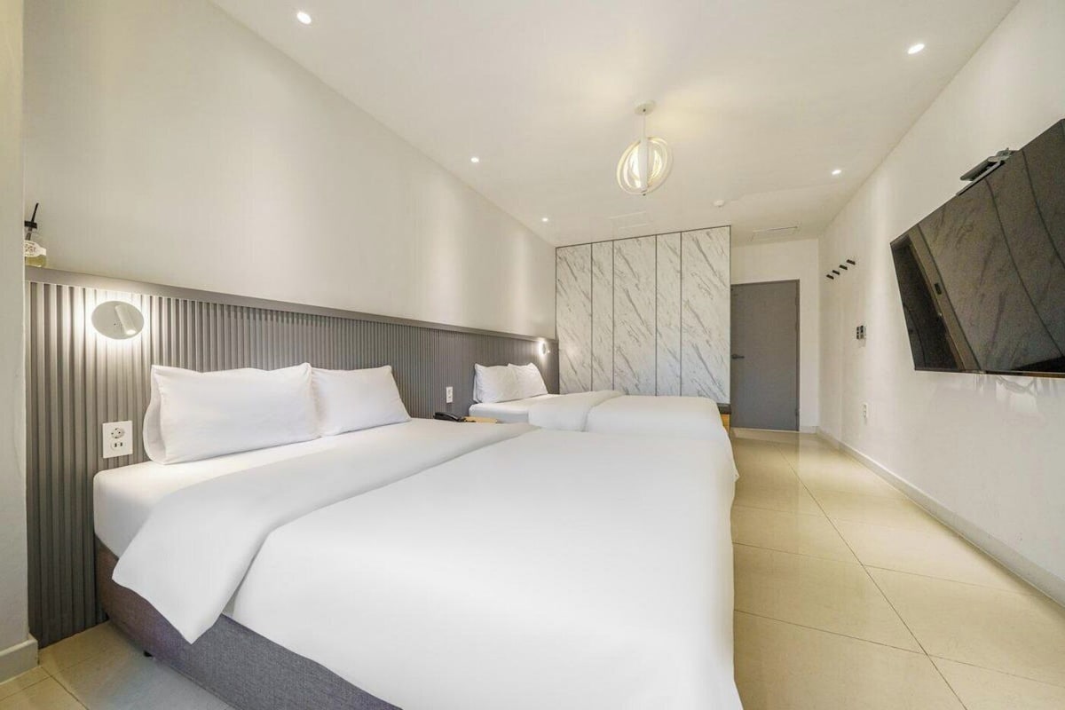 Een moderne hotelkamer met een groot bed, een flatscreen televisie aan de muur en een plafondlamp.