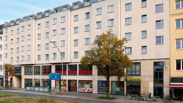 Ett hotell med flera våningar, en modern fasad, stora fönster och en tydligt markerad entré.