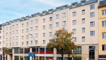 Un hôtel à plusieurs étages, doté d’une façade moderne, de grandes fenêtres et d’une entrée bien visible.
