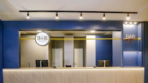 Een receptiebalie met een B&B logo, een bar en een modern design met verticale houten lamellen.