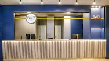 Un comptoir d’accueil orné du logo du B&B, un espace bar et un design moderne avec des lambris en bois verticaux.