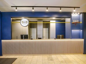 Un comptoir d’accueil orné du logo du B&B, un espace bar et un design moderne avec des lambris en bois verticaux.