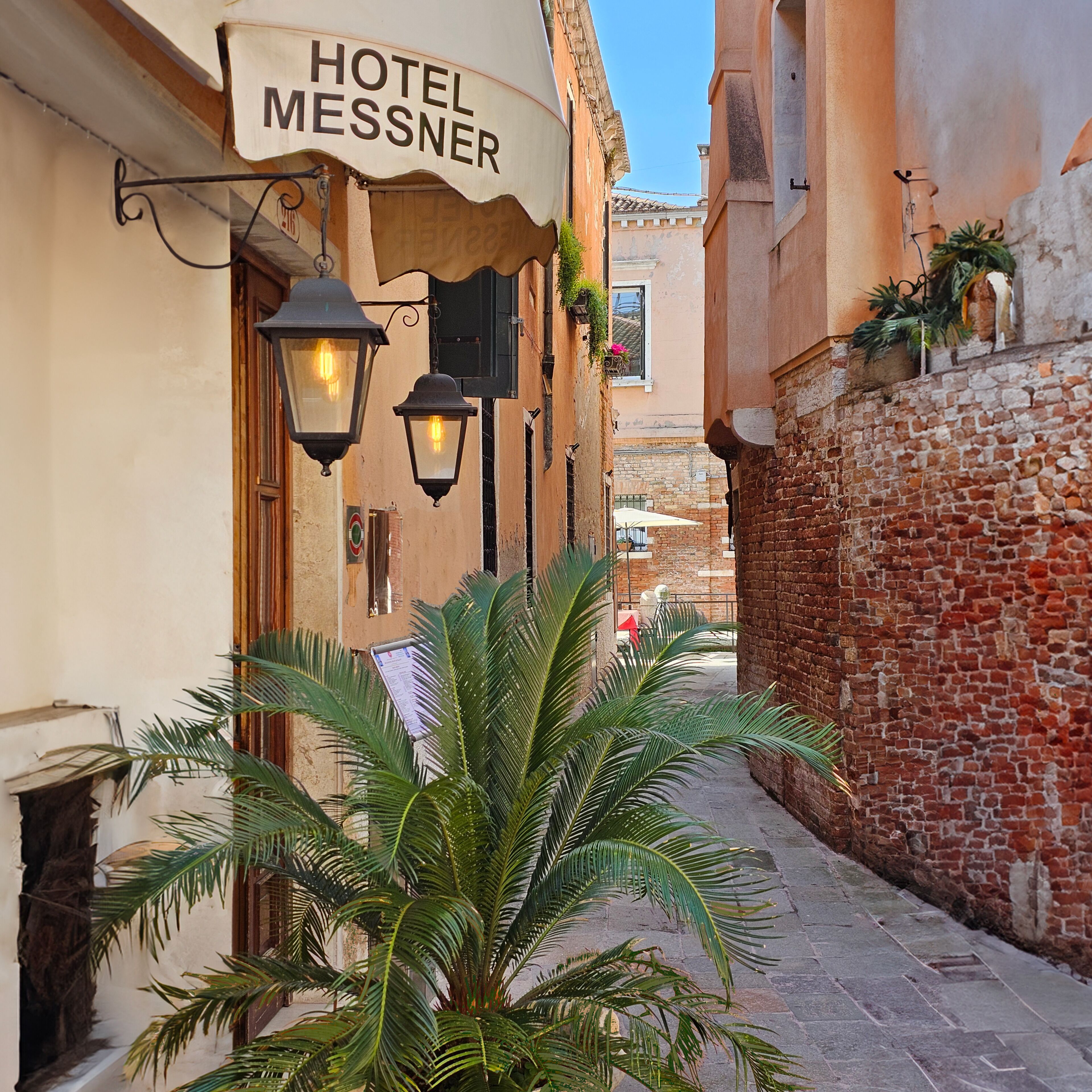 A narrow street with a building labeled "HOTEL MESSNER".