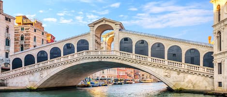 Un pont en pierre, doté de plusieurs arches, enjambe une rivière et est entouré de bâtiments historiques.