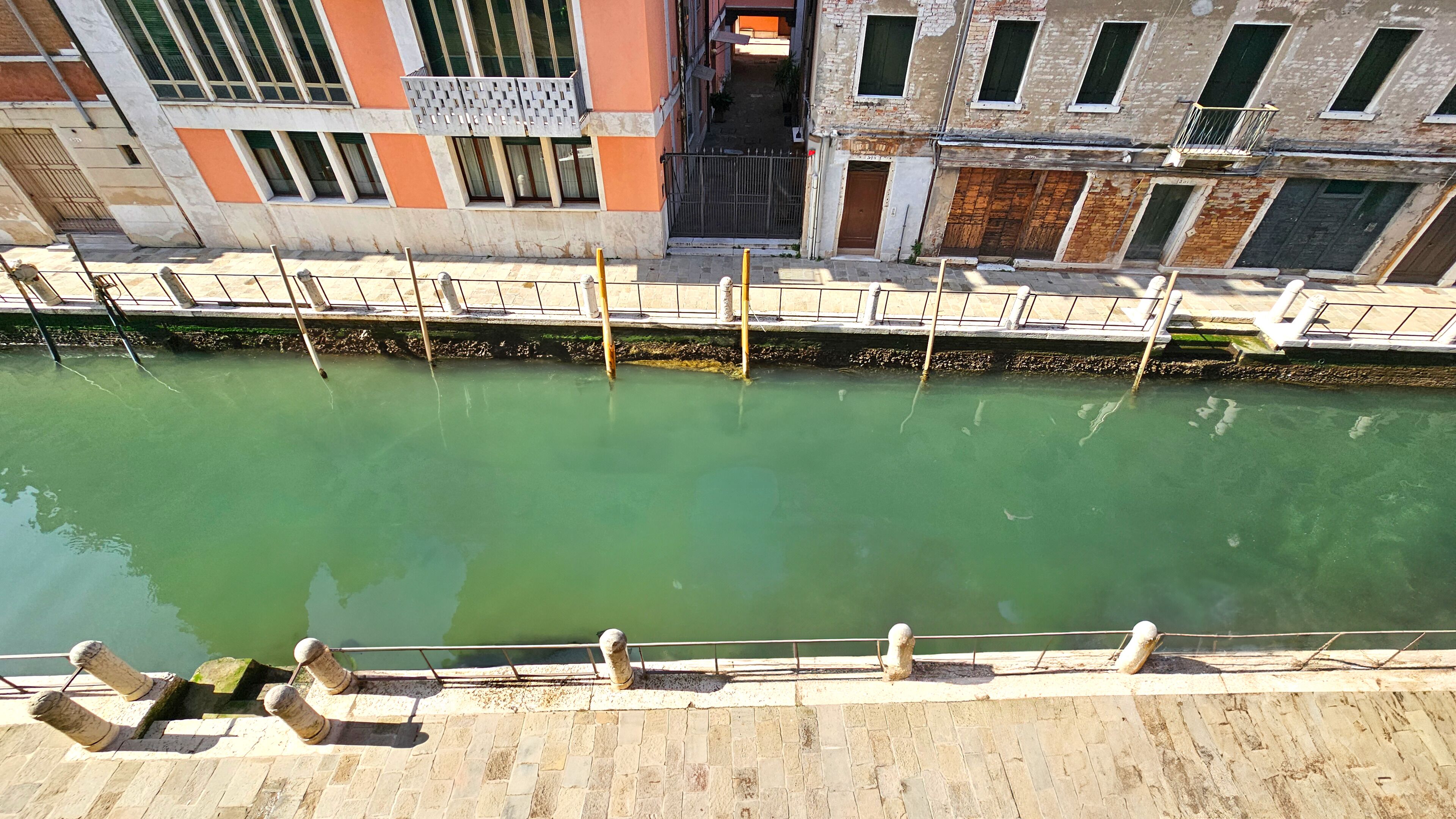 A canal with a stone walkway and metal railings.