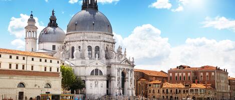A historic building with domes and statues, surrounded by water with gondolas.