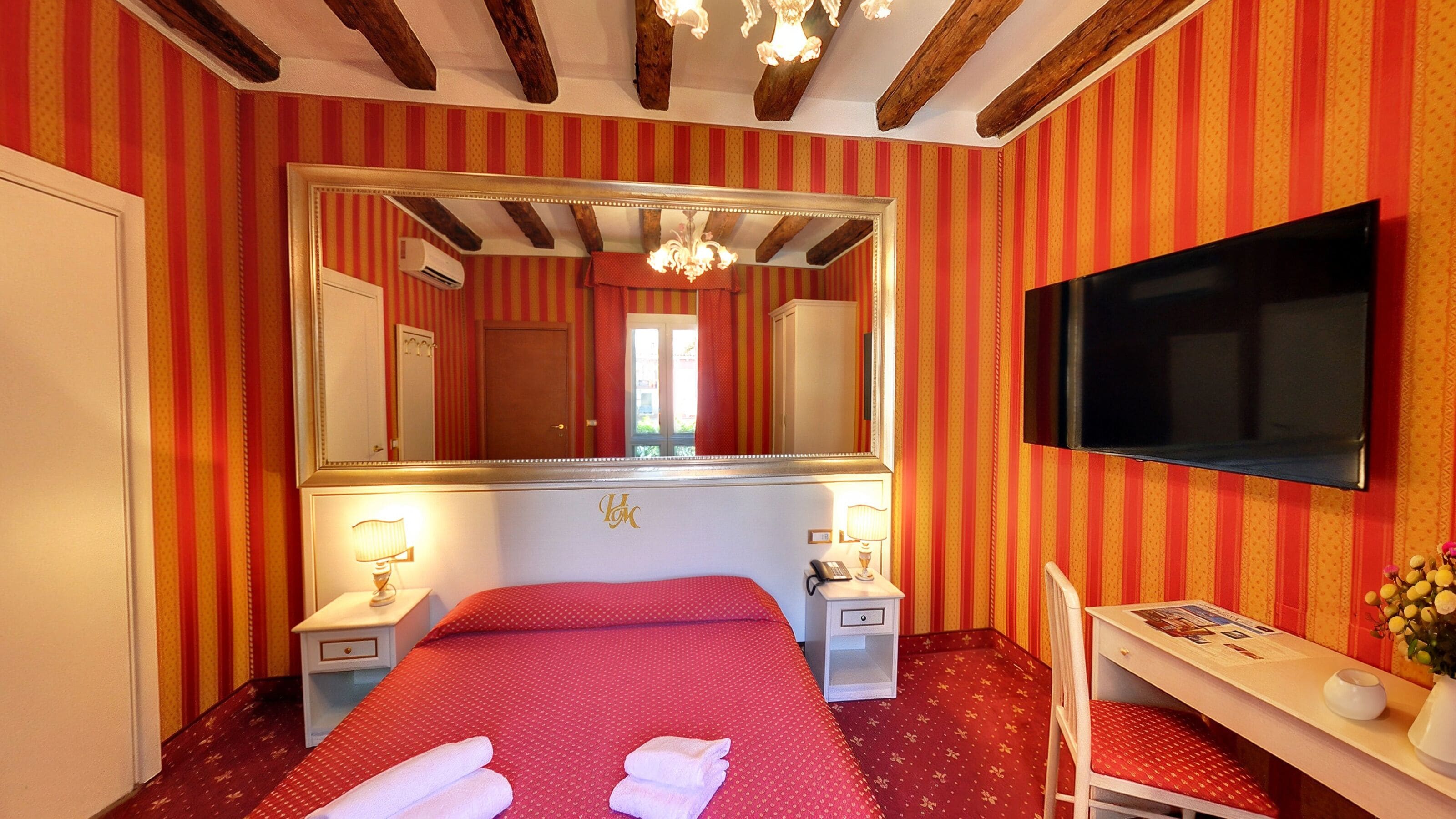 Una habitación de hotel con una cama grande, televisión, escritorio y espejo.