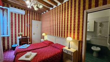 Une chambre avec deux lits, un bureau, une chaise, une lampe et un espace douche.