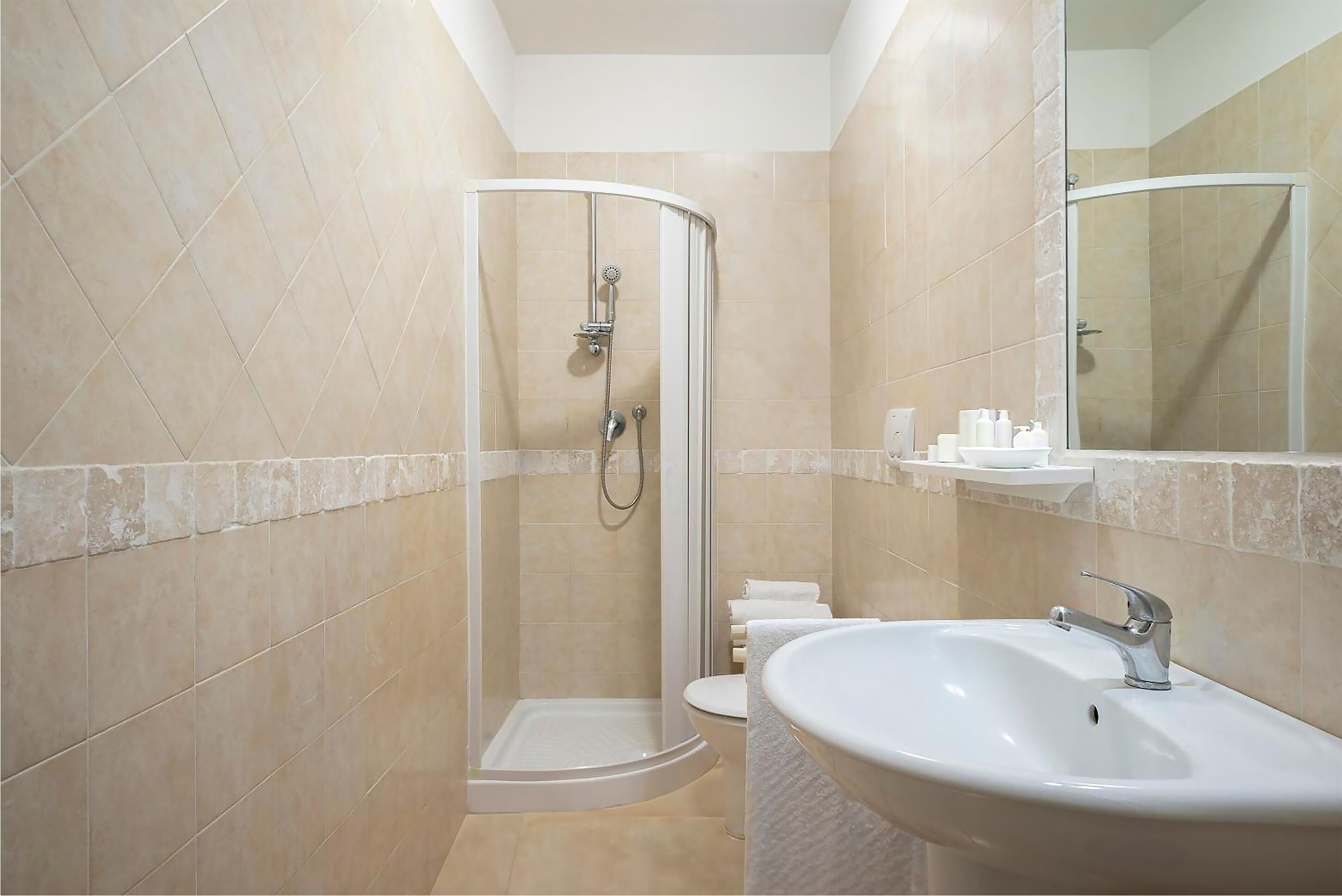 A bathroom with a shower, toilet, sink, and mirror.