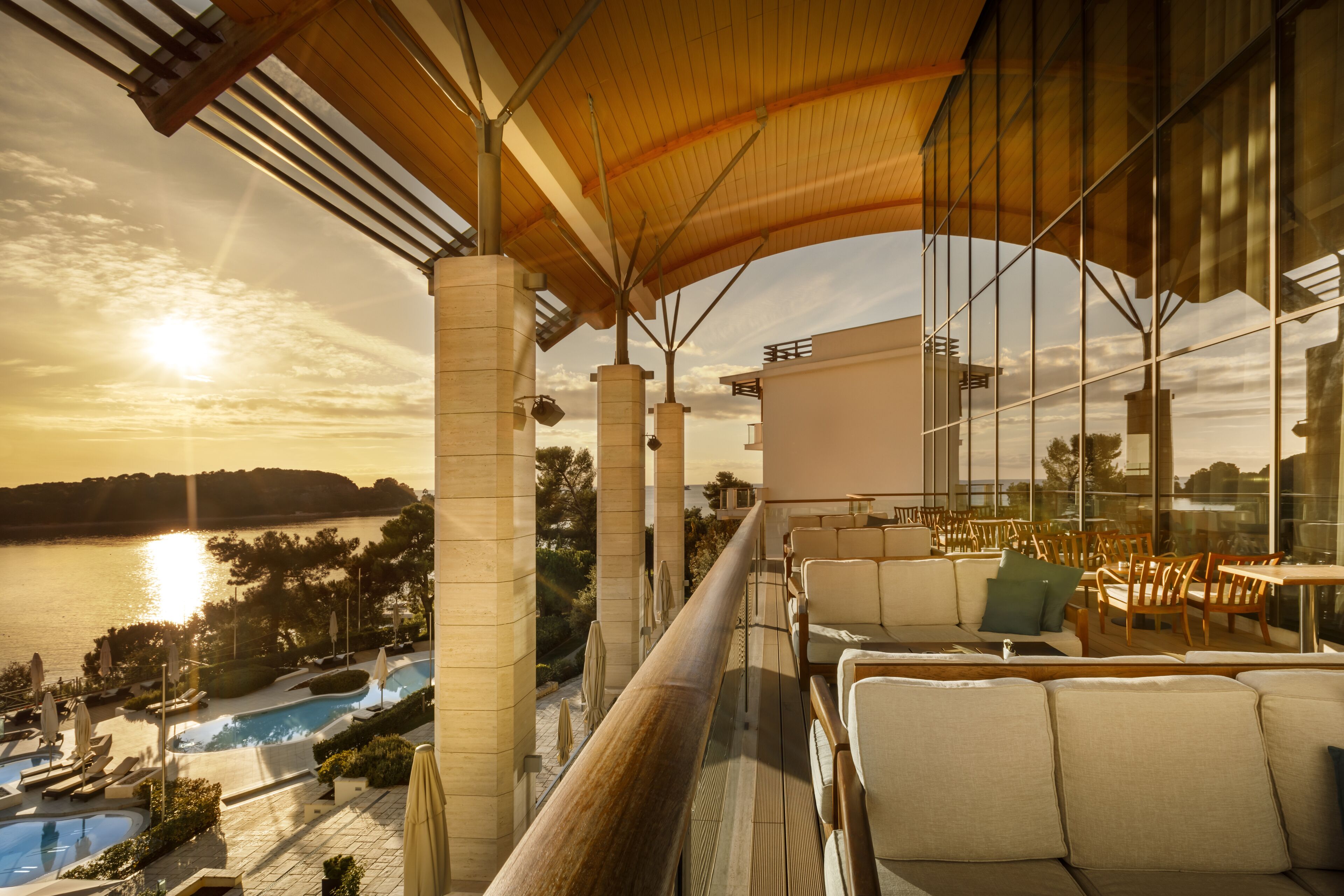Un balcón con vistas a una piscina y al atardecer.
