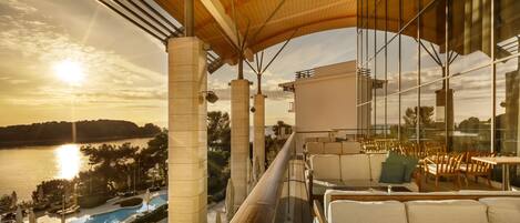 Un balcón con vistas a una piscina y al atardecer.