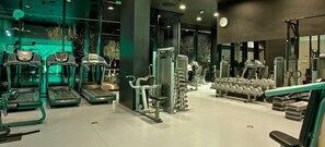 Un gimnasio moderno con cintas de correr, máquinas de pesas y pesas sueltas.