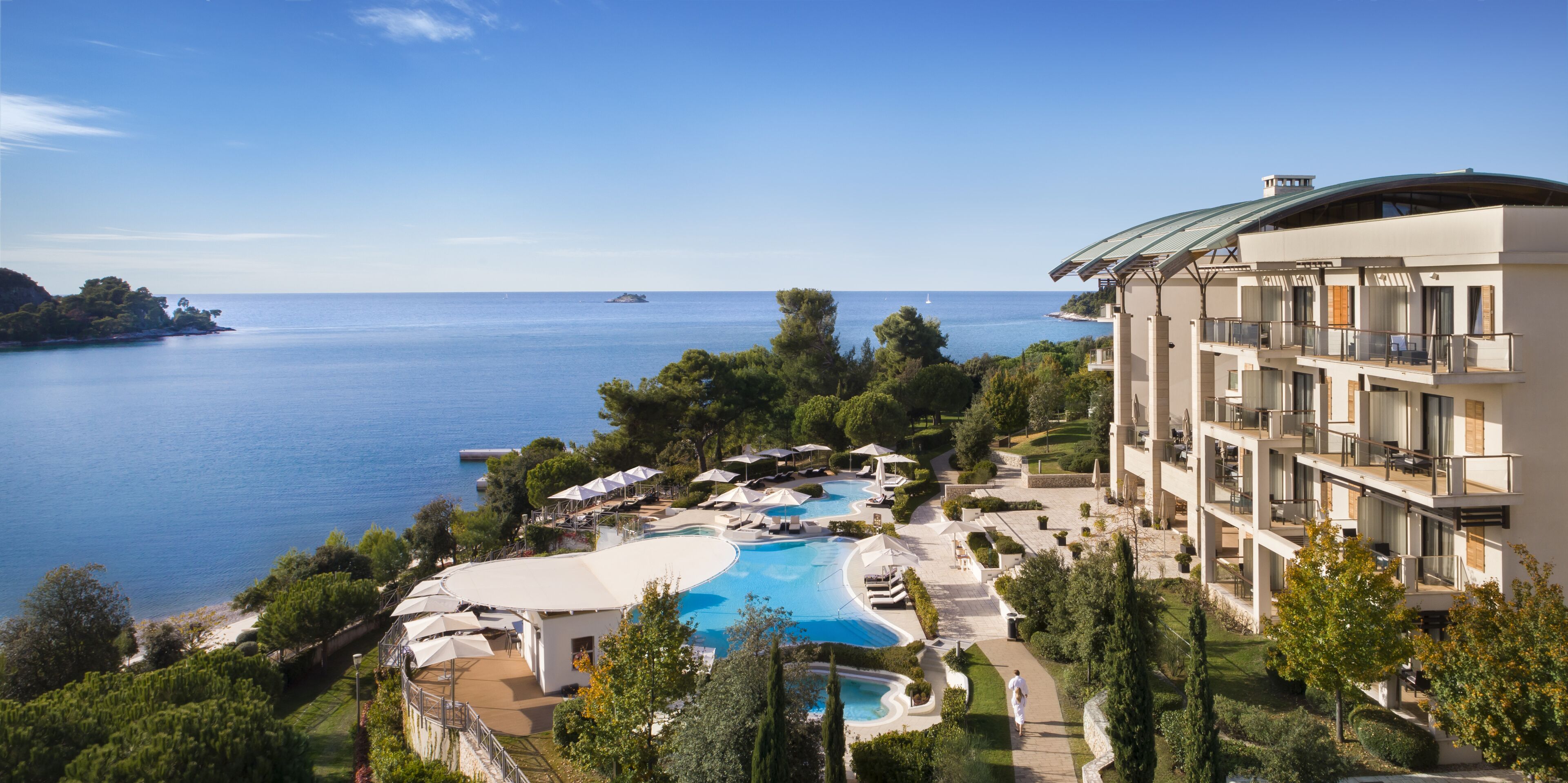Un resort con una piscina grande, varios balcones y vistas al mar.