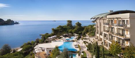 Un resort con una piscina grande, varios balcones y vistas al mar.