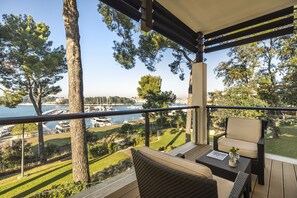 Un balcón con vista a un puerto deportivo, mobiliario exterior y una estructura de pérgola.