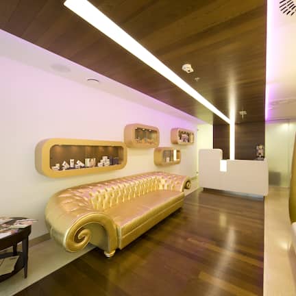 A reception area with a gold-colored sofa, a small table with papers, and a reception desk.