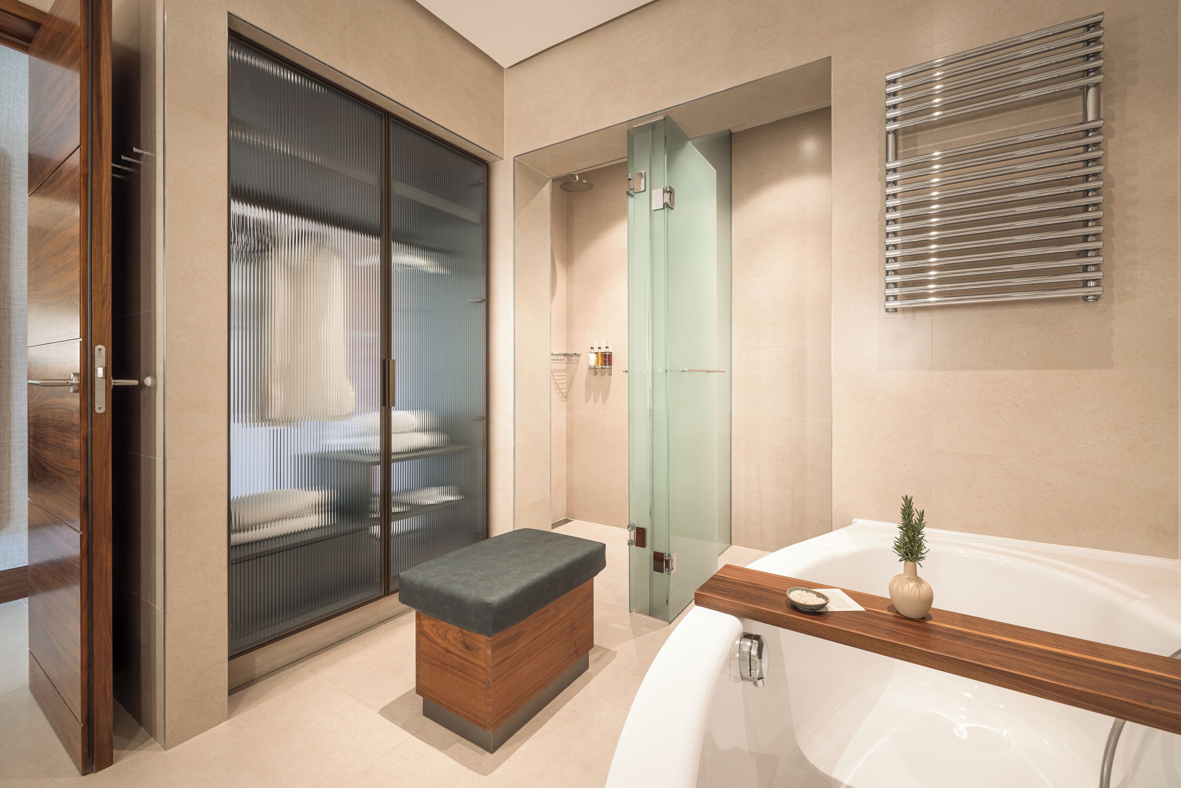 Un baño moderno con bañera, cabina de ducha de vidrio y banco de madera.