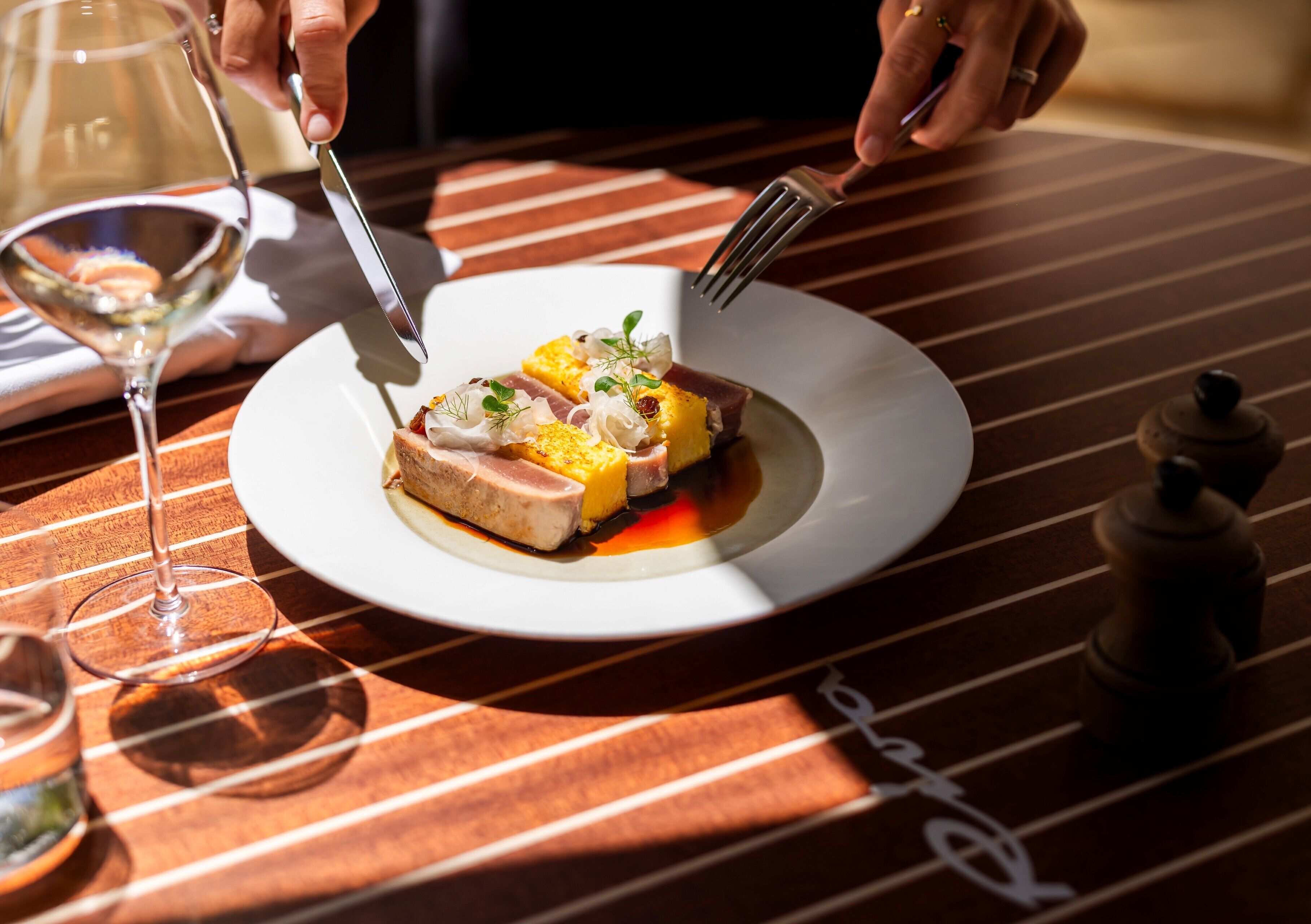 Une table à manger avec une assiette de nourriture, un verre à vin et un moulin à poivre.