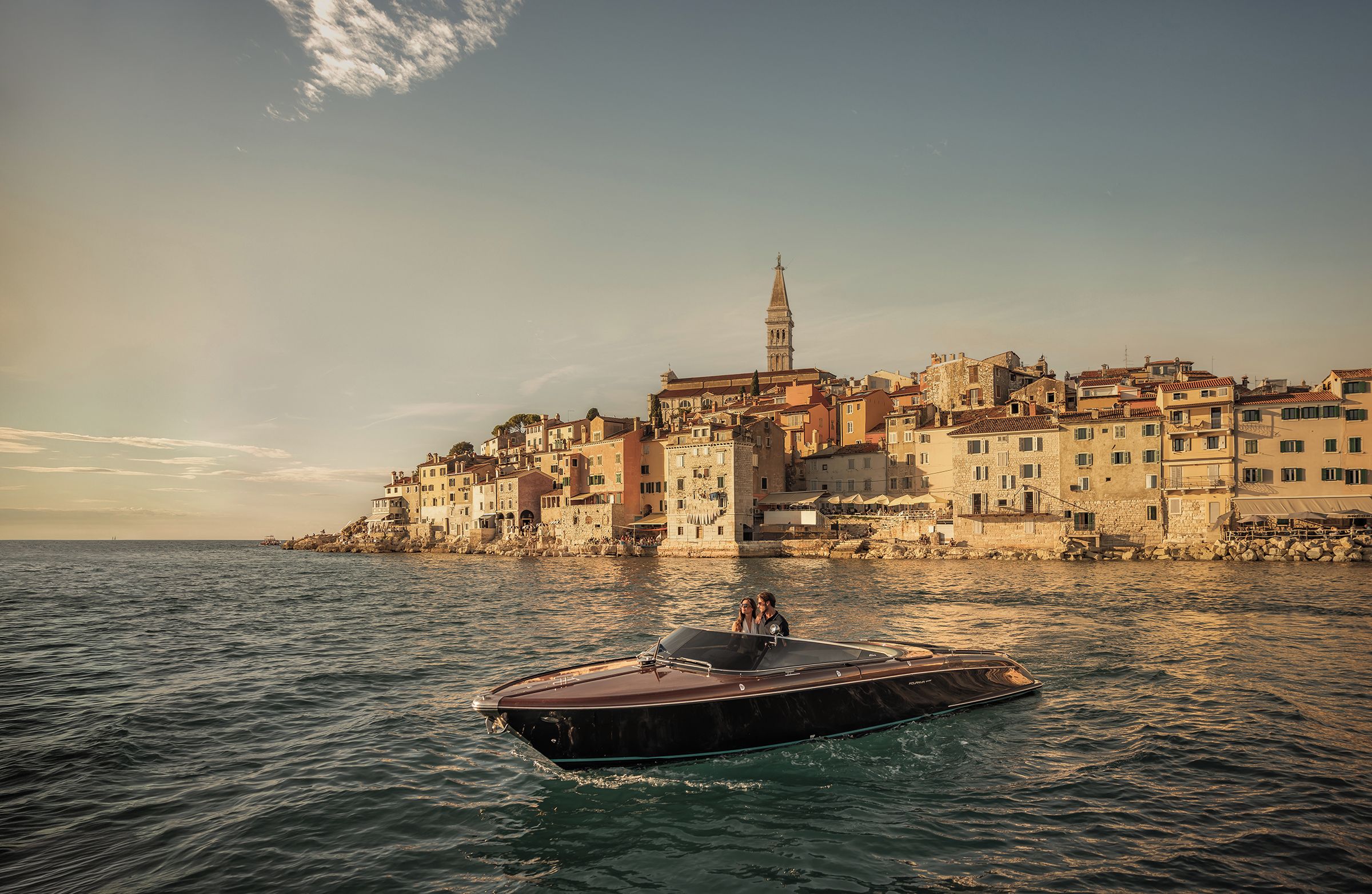 A coastal town with historic buildings, a prominent tower, and a boat in the foreground.