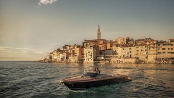 A coastal town with historic buildings, a prominent tower, and a boat in the foreground.