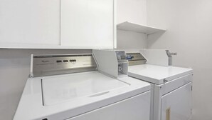 A white commercial washer with a control panel and a metal door. - Days Inn by Wyndham Seattle North of Downtown (Seattle)