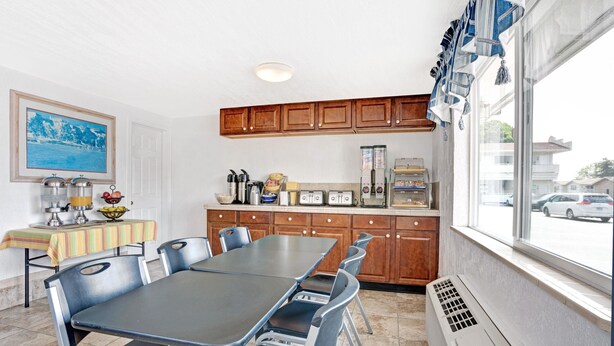 A kitchen with a dining table, chairs, wooden cabinets, a window, and a view of the outside. - Days Inn by Wyndham Seattle North of Downtown (Seattle)