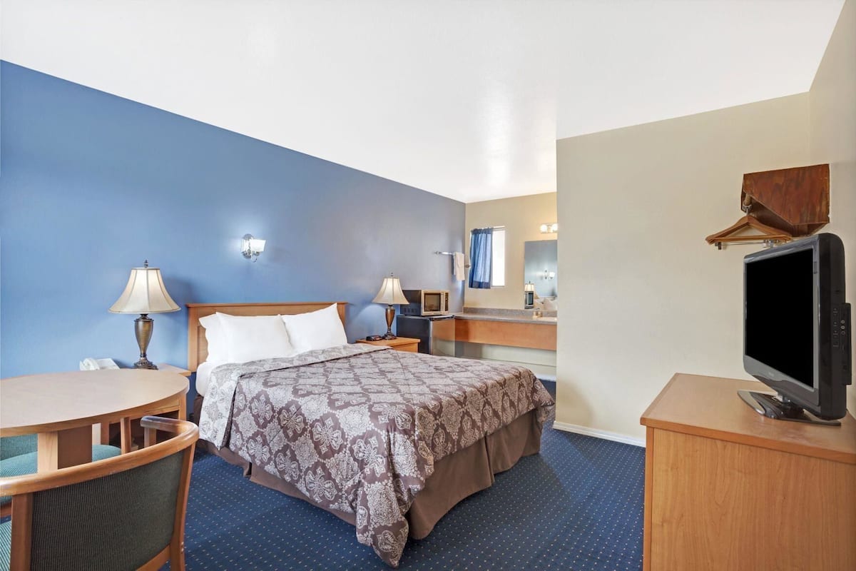 A hotel room with a bed, a desk, a chair, a television, and a bathroom.