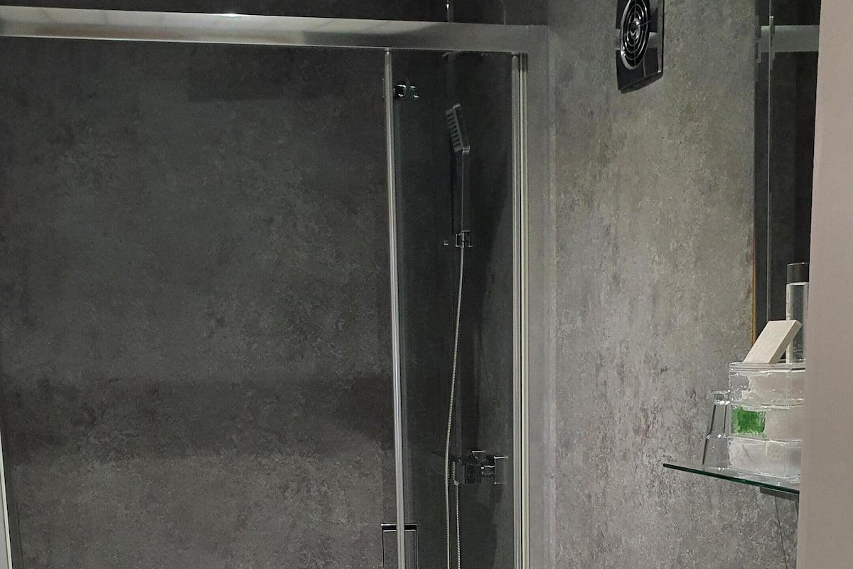 A modern bathroom with a glass-enclosed shower, a white toilet, a white sink, and a mirror.