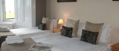 A hotel room with two beds, a window, a painting, and a lamp.