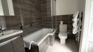 A modern bathroom with a bathtub, toilet, and sink.