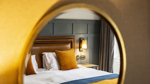 Une chambre d’hôtel avec un grand lit, une tête de lit, une table de chevet et une lampe fixée au mur.