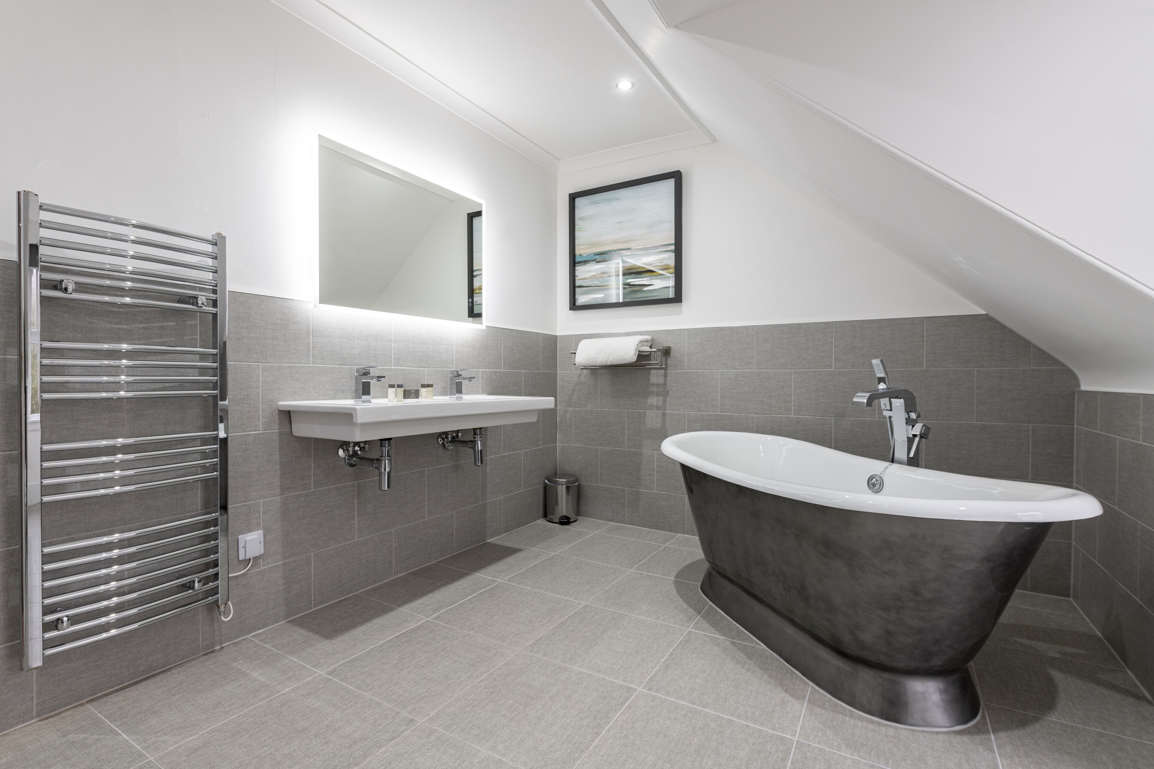A modern bathroom with a freestanding bathtub, a vanity with a mirror, and a towel rack.